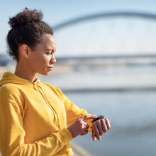 Mid adult African American woman using touch screen smart watch to check why her heart rate is high on an easy run