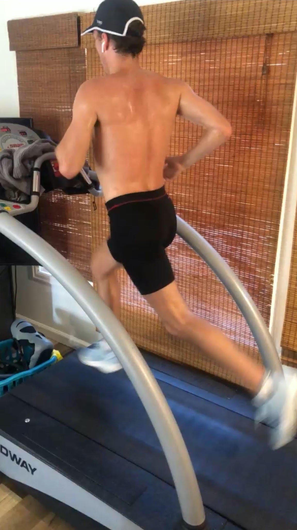 Man running on a treadmill facing away from the camera.