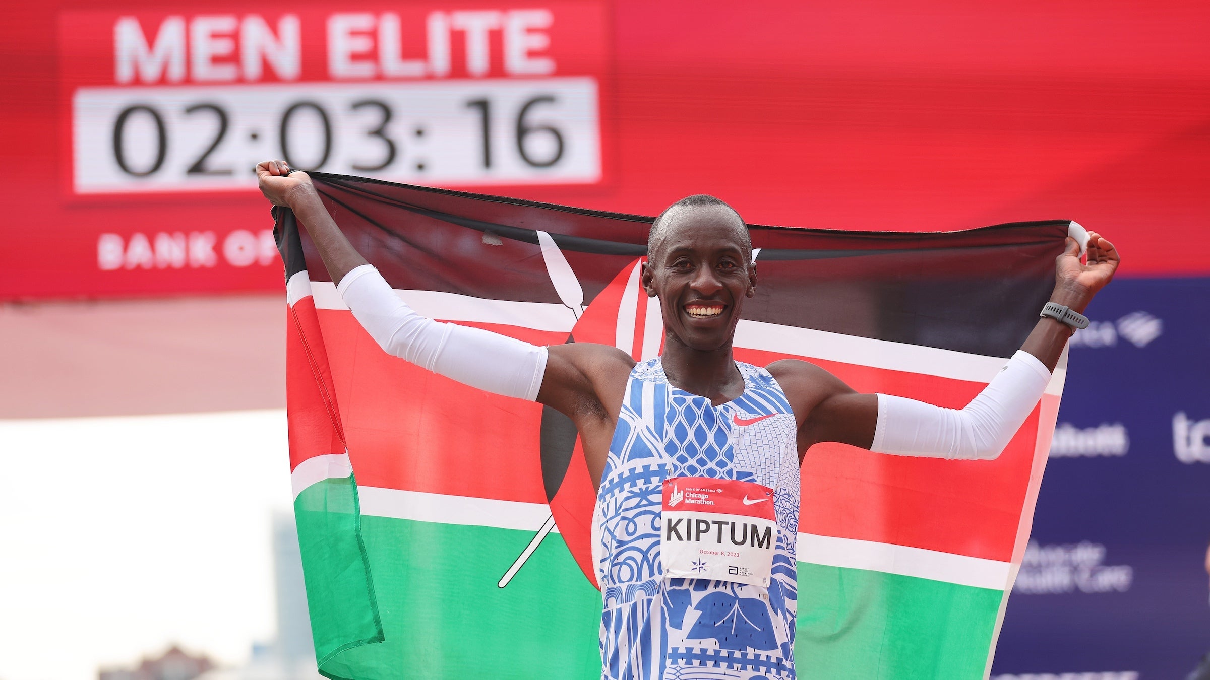 A man celebrates after winning a marathon with a red and green flag