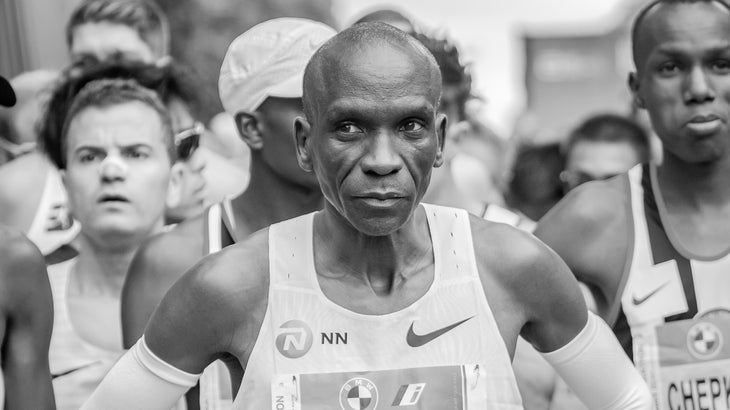 Kipchoge, an elite marathoner at the start line, in a white singlet.