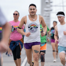 a man with a butterfly tattoo on his thigh and a pride shirt runs a 5K in Portland