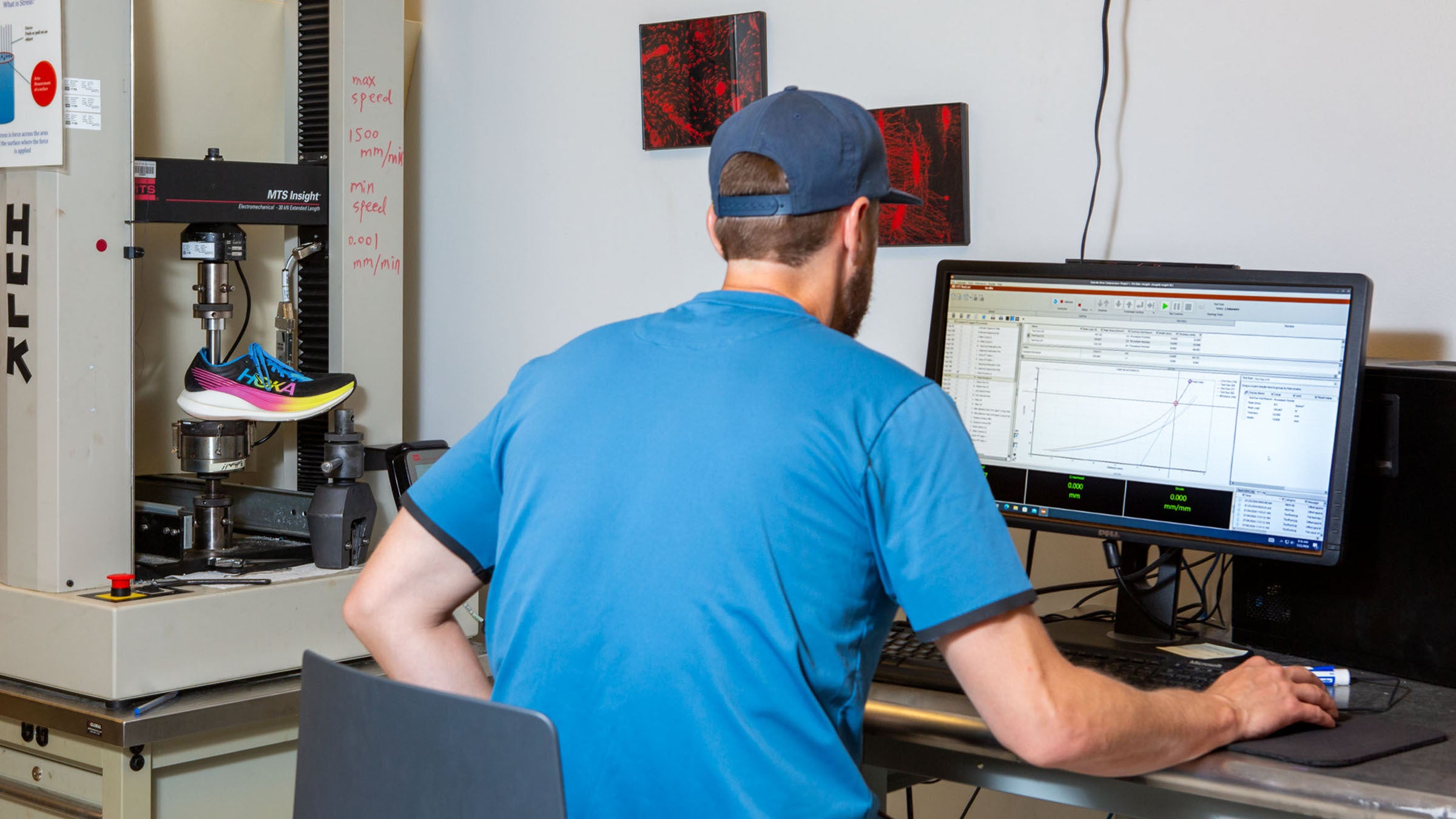 Man sitting at computer evaluating graph next to compression tester