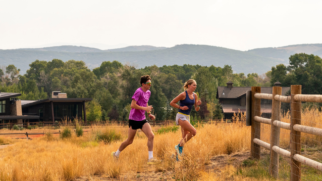 two runners running next to a fence in Park City