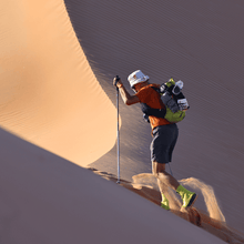 A runner hikes up a sand dune during the Oman Desert Marathon stage race.