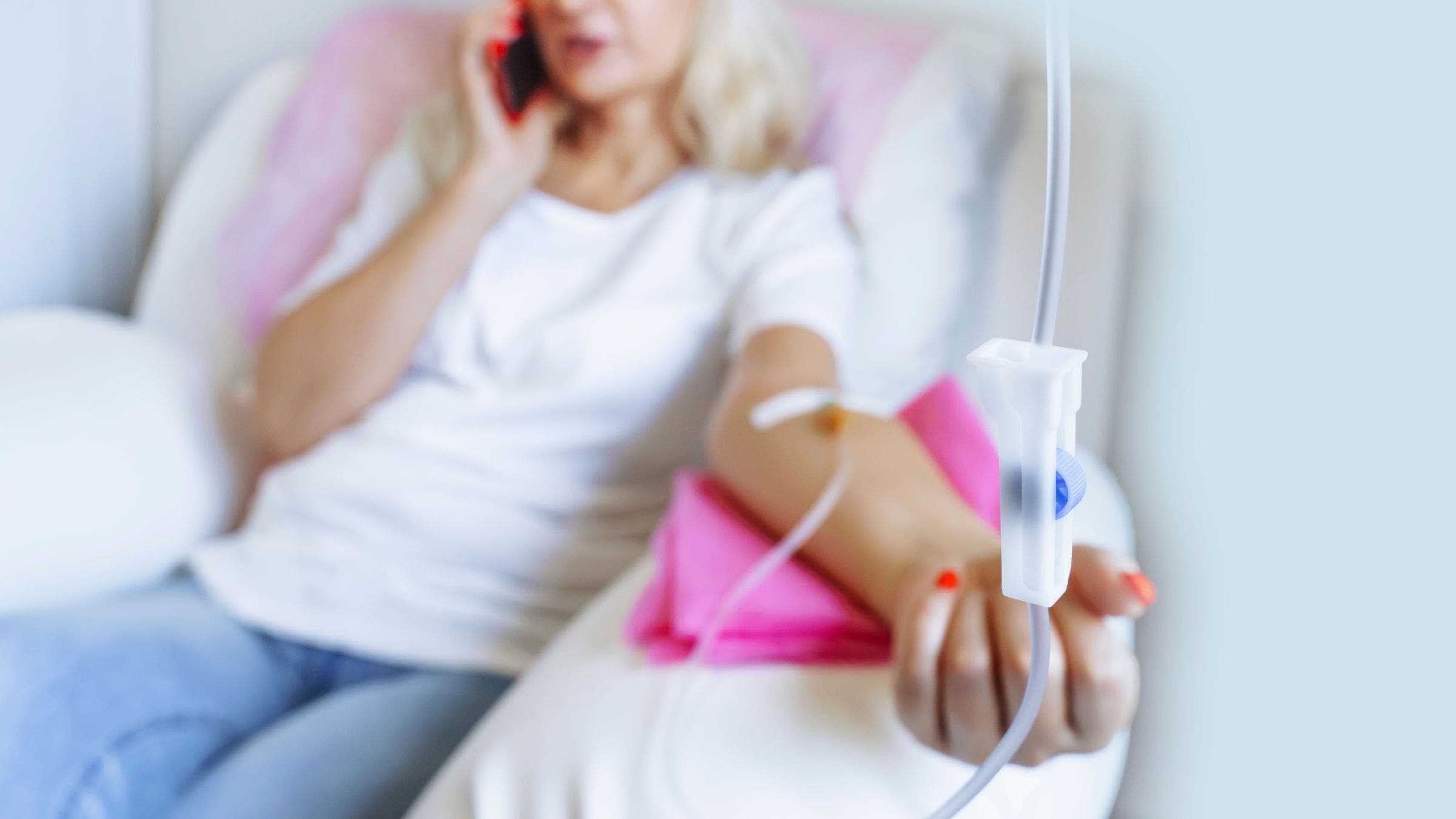 a woman chats on her phone while enjoying an IV drip