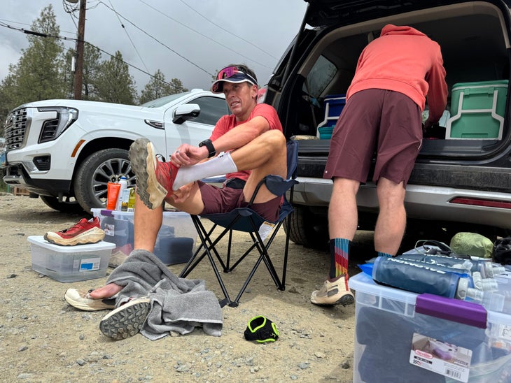 A runner in a camp chair changes a shoe.