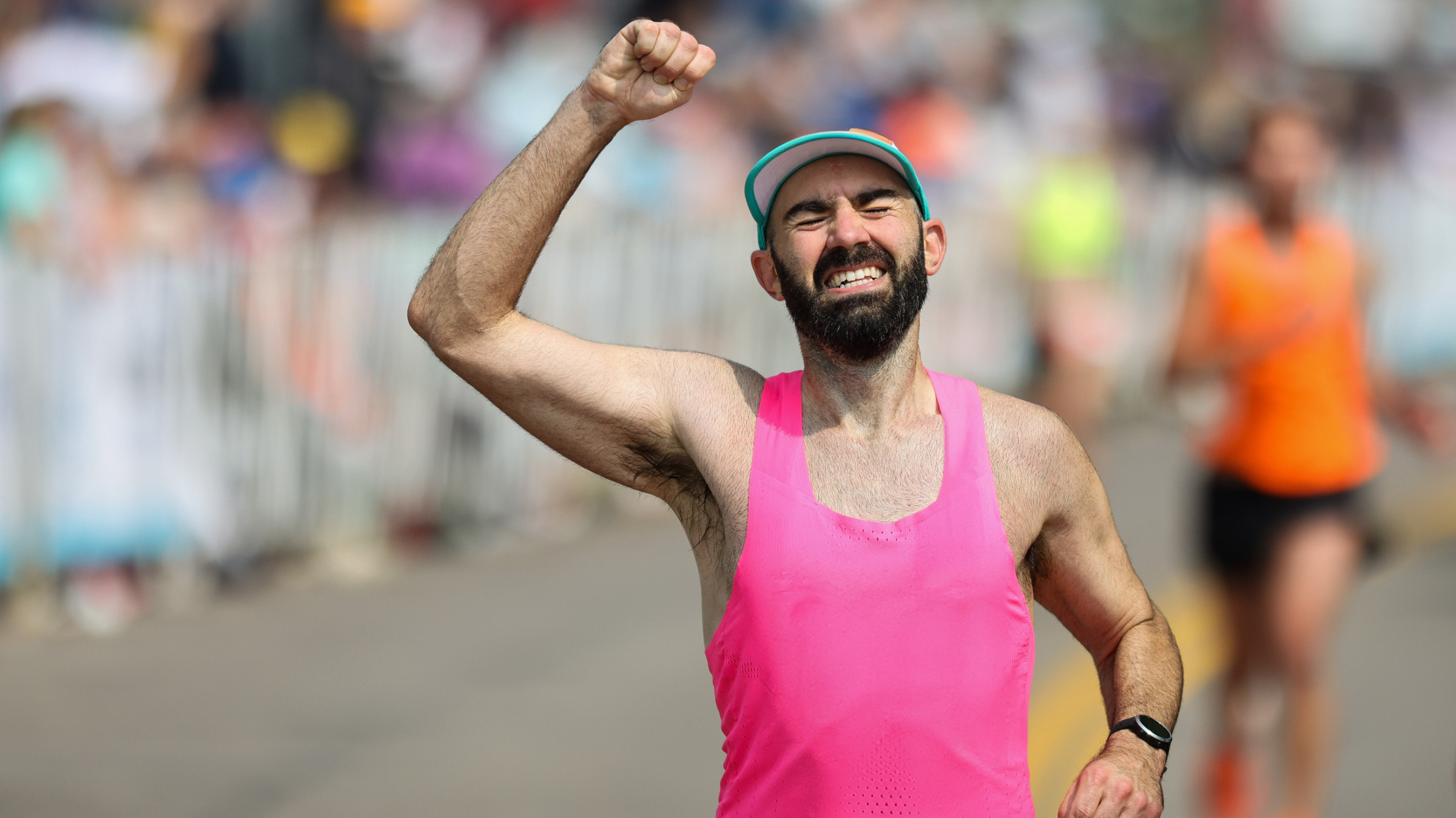 a man in a pink singlety crossing the finish line inpain