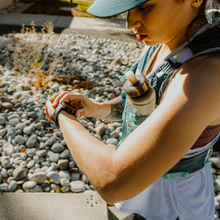 a woman in a hydration vest chcks her heart rate before going on a run