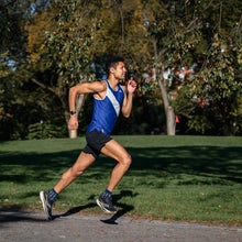A man runs quickly in a blue singlet