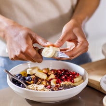 close up of woman making healthy breakfast in kitchen with fruits and yogurt