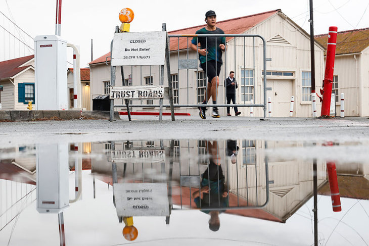 A runner moves past a gate closing the road to Fort Point National Historic Site from Crissy Field in San Francisco, California Wednesday, Oct. 1, 2025