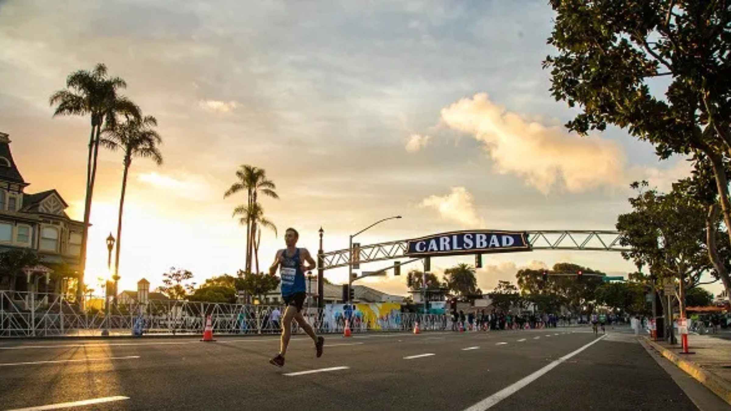 runner next to a carslbad sign running near palm trees