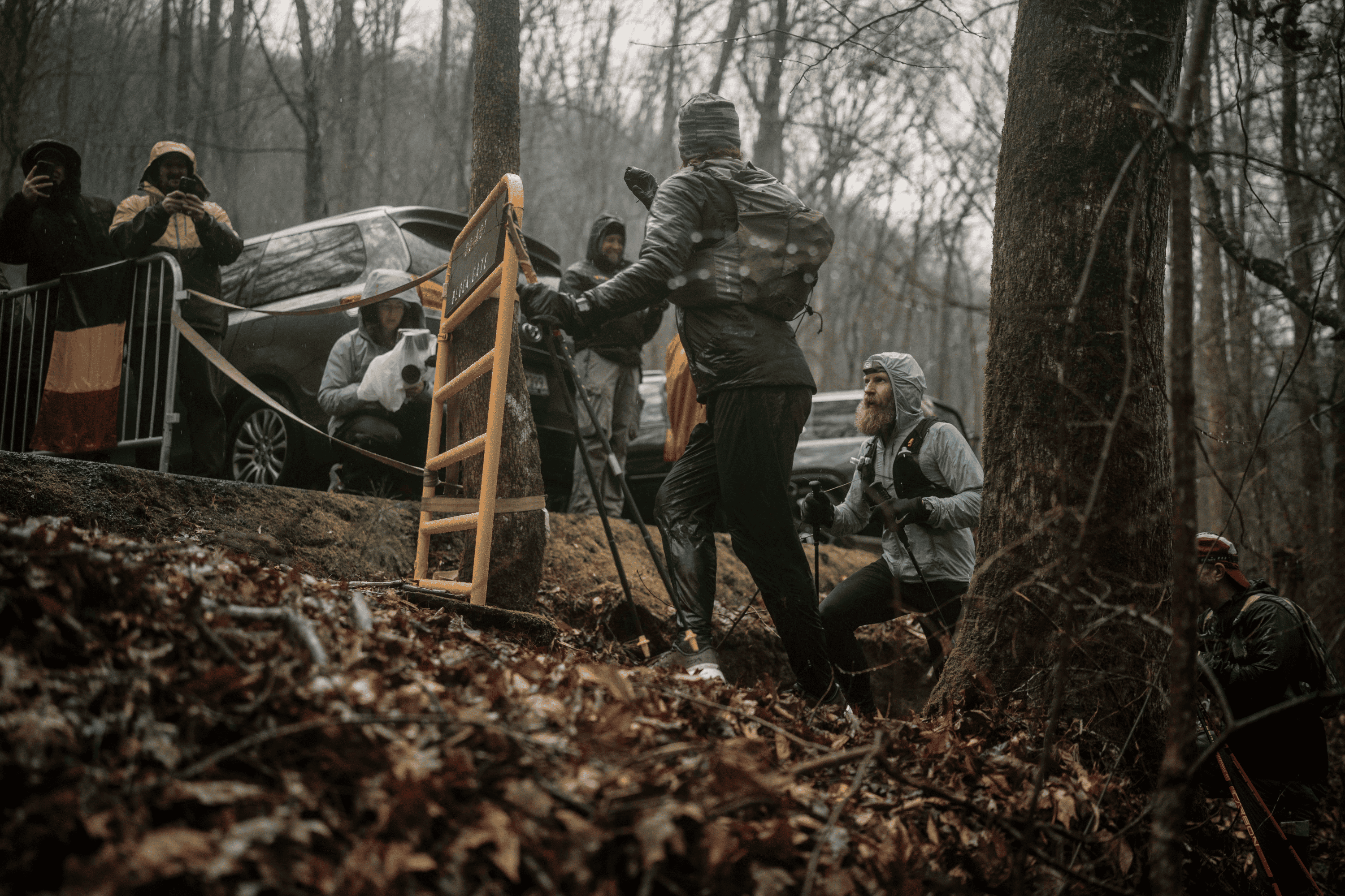 The rain is coming down, and the character of the race is changing. Everyone in camp seeks shelter somewhere—cars, tents, and whatever they can find. Meanwhile out on course, the remaining runners face difficult terrain made even more challenging by fog and slippery mud.