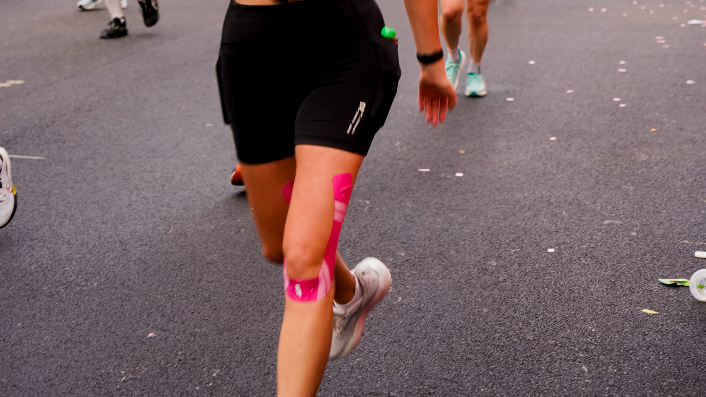 a woman with pink KT tape runs a race