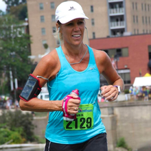 a woman in a torquoise shirt in her 50s running a marathon