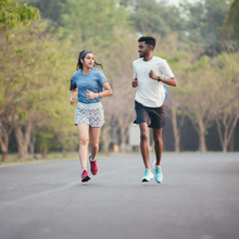 two people running on a tree-lined road
